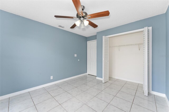 unfurnished bedroom with baseboards, visible vents, a ceiling fan, a closet, and light tile patterned flooring