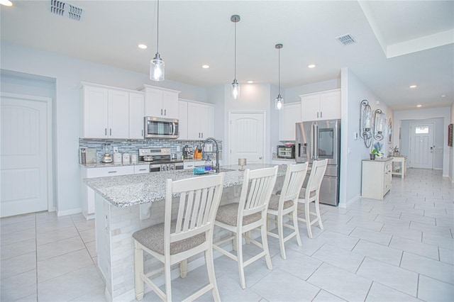 kitchen with stainless steel appliances, tasteful backsplash, a kitchen bar, and visible vents