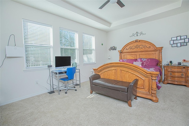 bedroom featuring carpet floors, a tray ceiling, baseboards, and a ceiling fan