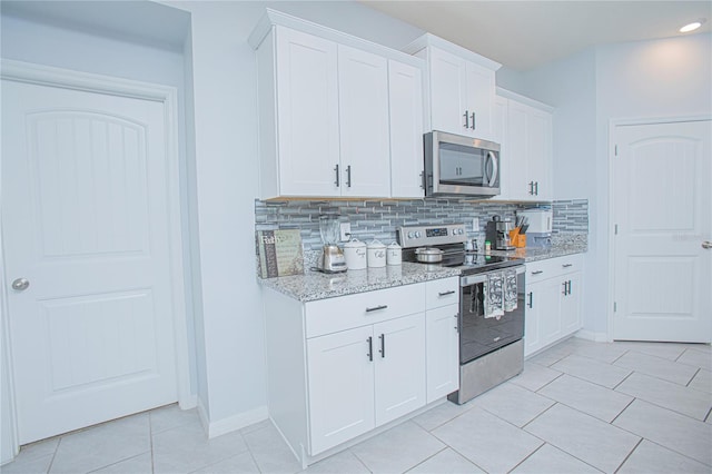 kitchen featuring light tile patterned floors, light stone counters, stainless steel appliances, white cabinetry, and tasteful backsplash