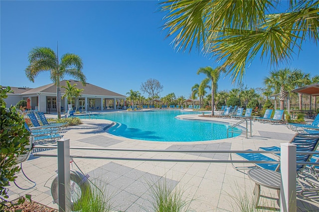 community pool with a patio area and fence