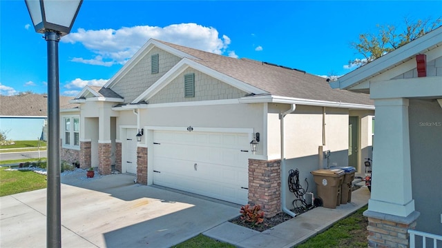 view of home's exterior featuring a garage, stone siding, driveway, and stucco siding