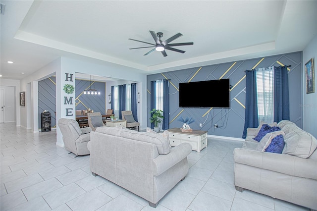 living area with an accent wall, a tray ceiling, and baseboards