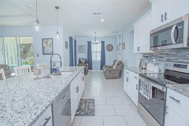 kitchen with stainless steel appliances, tasteful backsplash, a sink, and visible vents