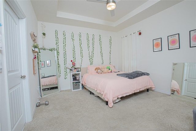 bedroom featuring ceiling fan, a tray ceiling, carpet, and baseboards