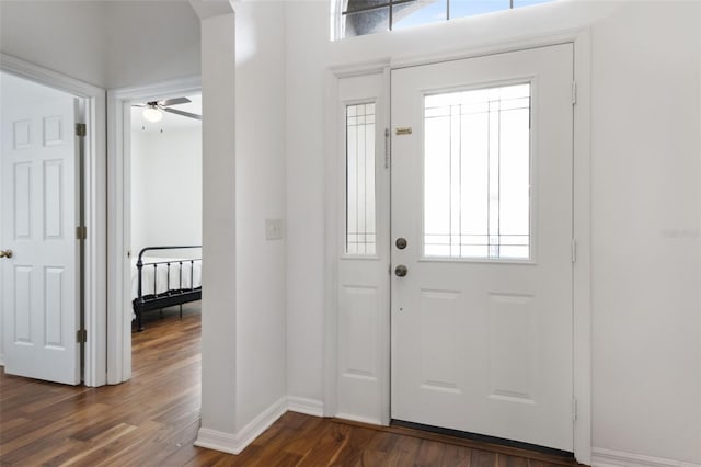 entryway with arched walkways, ceiling fan, dark wood finished floors, and baseboards