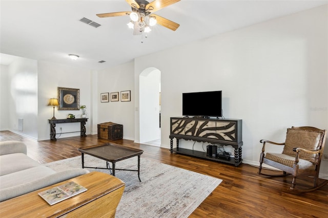 living area with visible vents, arched walkways, dark wood finished floors, baseboards, and ceiling fan