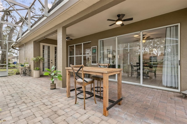 view of patio with outdoor dining space, glass enclosure, and ceiling fan