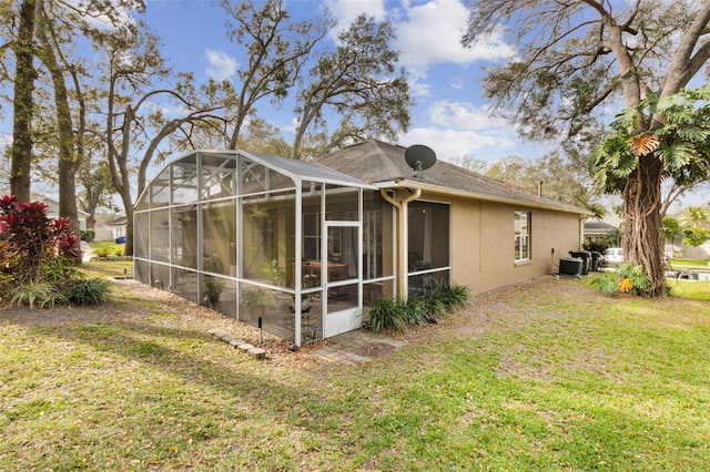 back of house with central AC, a lawn, and stucco siding