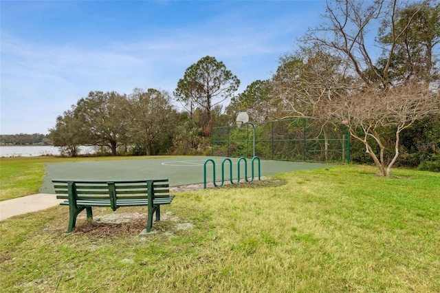 view of community featuring community basketball court, a water view, and a lawn