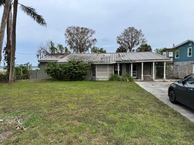 ranch-style home featuring metal roof, fence, and a front lawn