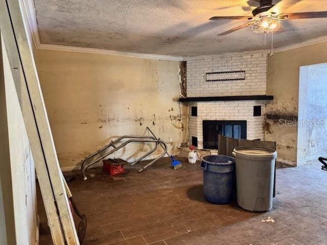 living area featuring a ceiling fan, ornamental molding, wood finished floors, a textured ceiling, and a brick fireplace