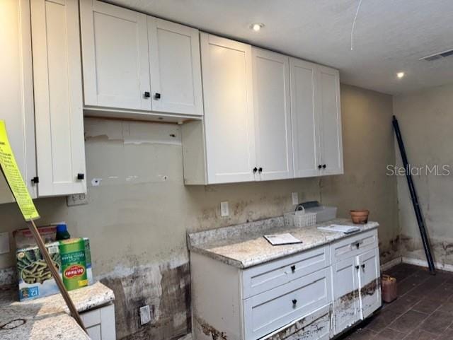 kitchen featuring visible vents, baseboards, light stone countertops, white cabinetry, and recessed lighting