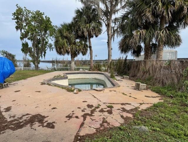 view of swimming pool featuring fence and a jacuzzi