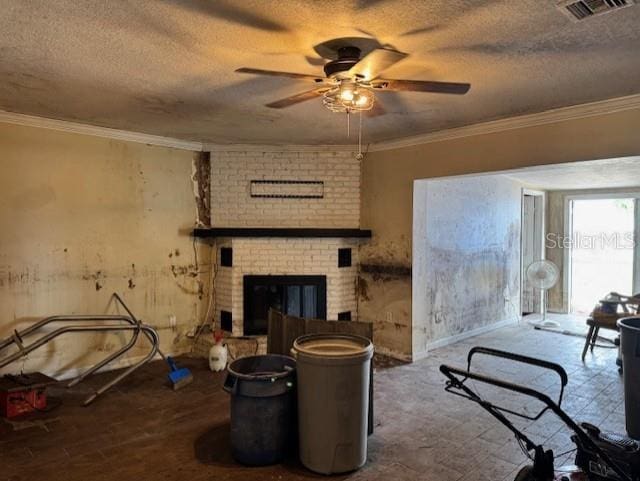 living room with a textured ceiling, ceiling fan, visible vents, a brick fireplace, and crown molding