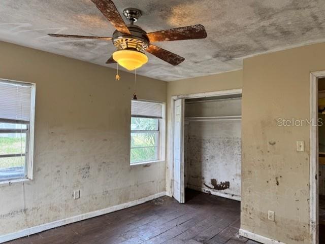 unfurnished bedroom featuring dark wood-style floors, a closet, and ceiling fan