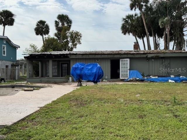 rear view of property featuring a chimney and a lawn