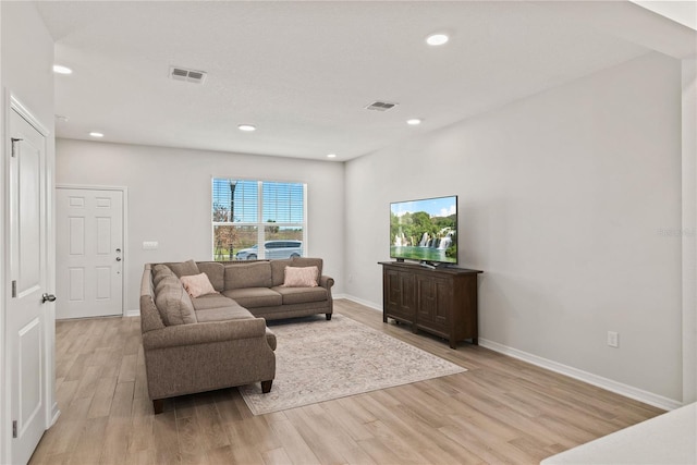 living area featuring light wood-style floors, visible vents, and baseboards