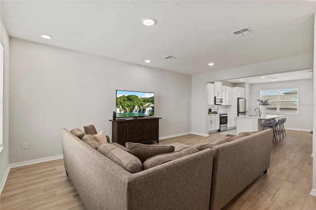 living room with light wood-style floors, recessed lighting, visible vents, and baseboards