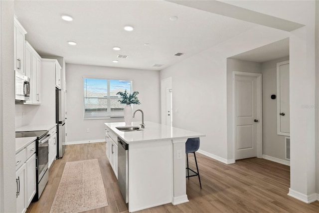 kitchen featuring a sink, white cabinets, light countertops, appliances with stainless steel finishes, and an island with sink