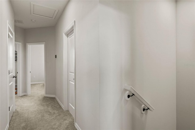 hall featuring baseboards, visible vents, attic access, and light colored carpet