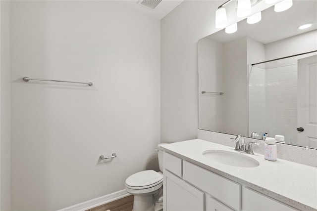 bathroom with toilet, wood finished floors, visible vents, vanity, and baseboards