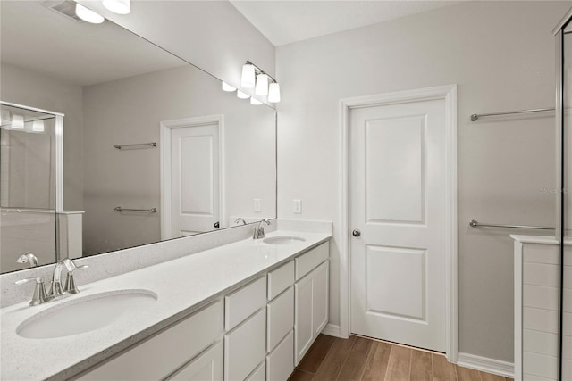 bathroom featuring double vanity, wood finished floors, and a sink