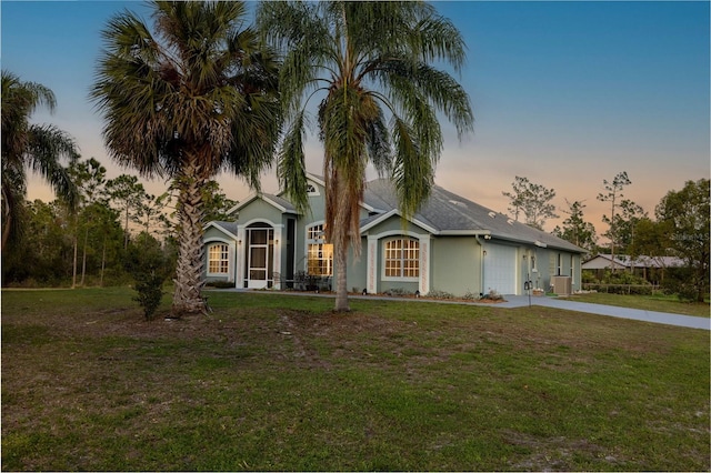 ranch-style home featuring stucco siding, driveway, an attached garage, and a lawn