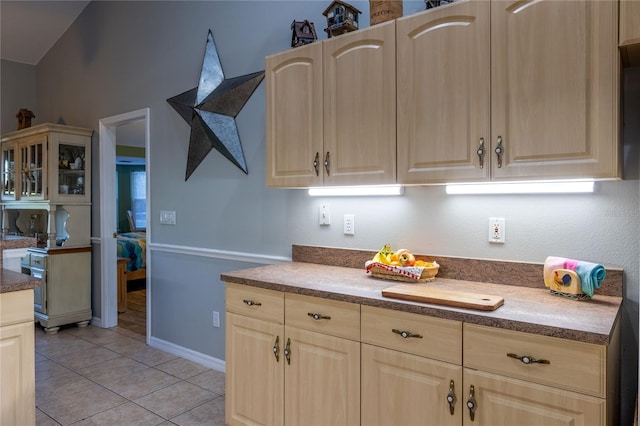 kitchen with light tile patterned floors, light brown cabinets, and baseboards