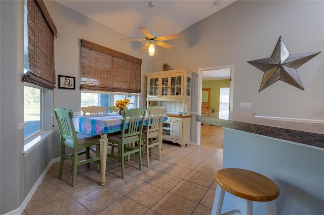 dining area featuring light tile patterned flooring, ceiling fan, a towering ceiling, and baseboards