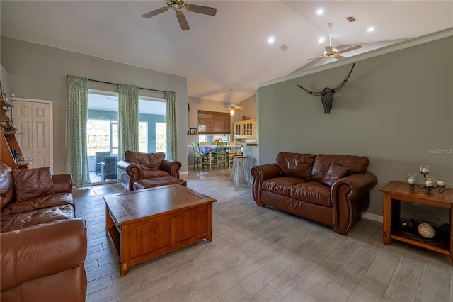 living area featuring light wood-style floors, visible vents, vaulted ceiling, and a ceiling fan