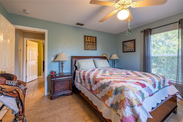 bedroom featuring light wood-style floors, visible vents, and ceiling fan