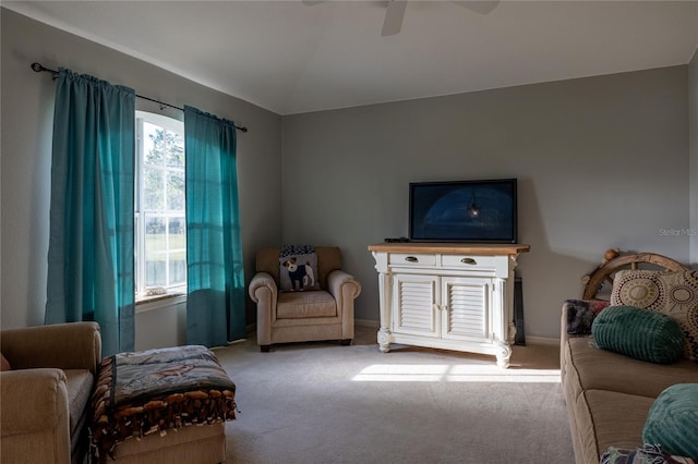 sitting room with light carpet, vaulted ceiling, a ceiling fan, and baseboards