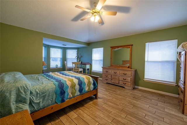 bedroom with light wood-style flooring, baseboards, and ceiling fan