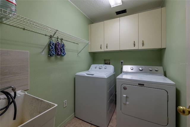 laundry area featuring cabinet space, light tile patterned floors, visible vents, independent washer and dryer, and a sink