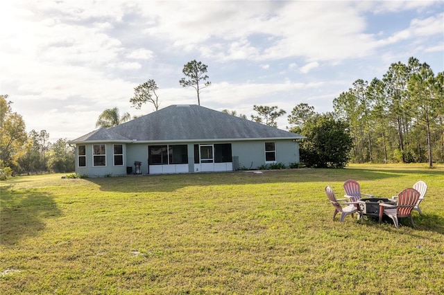 rear view of house featuring an outdoor fire pit and a lawn