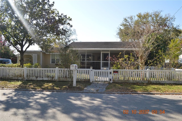 single story home featuring a sunroom and a fenced front yard