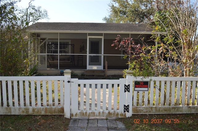 view of front of home featuring a fenced front yard, a gate, and a sunroom