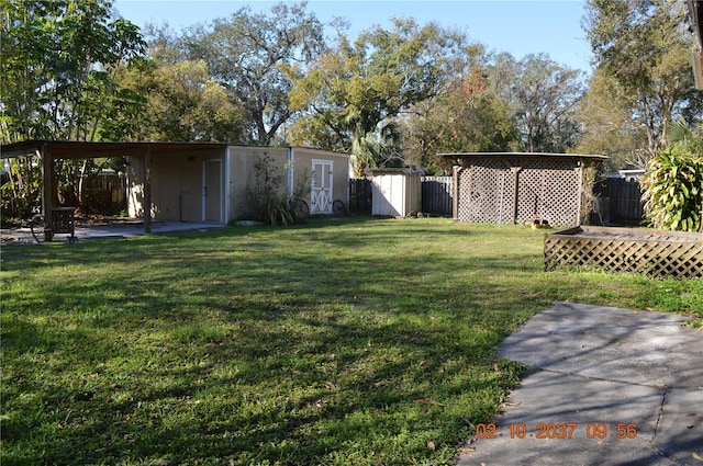 view of yard featuring a storage shed, a patio area, fence, and an outbuilding