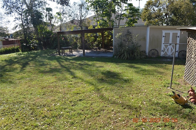 view of yard with an outdoor structure, fence, and a storage unit