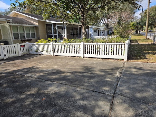 exterior space with a sunroom, a fenced front yard, and a gate