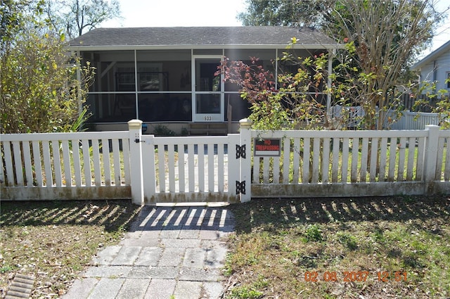 view of front of property with a fenced front yard, a gate, and a sunroom