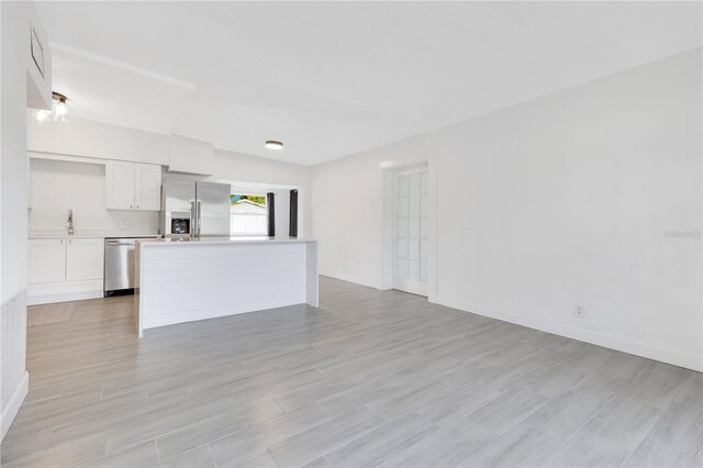 unfurnished living room with light wood-style flooring and baseboards