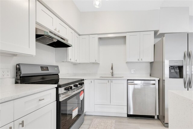 kitchen with white cabinets, light stone counters, stainless steel appliances, under cabinet range hood, and a sink