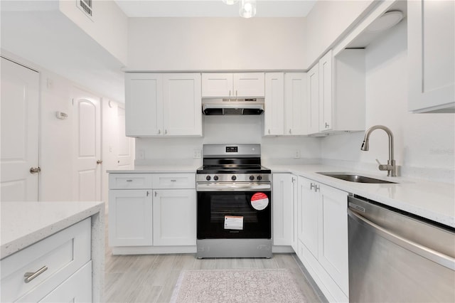 kitchen with under cabinet range hood, white cabinetry, appliances with stainless steel finishes, and a sink