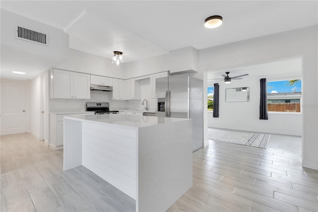 kitchen featuring under cabinet range hood, visible vents, white cabinets, light countertops, and appliances with stainless steel finishes