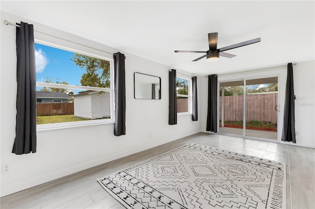 spare room with wood finished floors, a ceiling fan, and baseboards