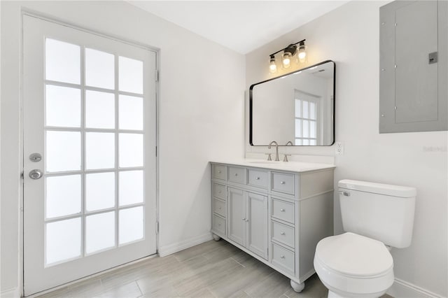 bathroom featuring toilet, vanity, electric panel, and baseboards