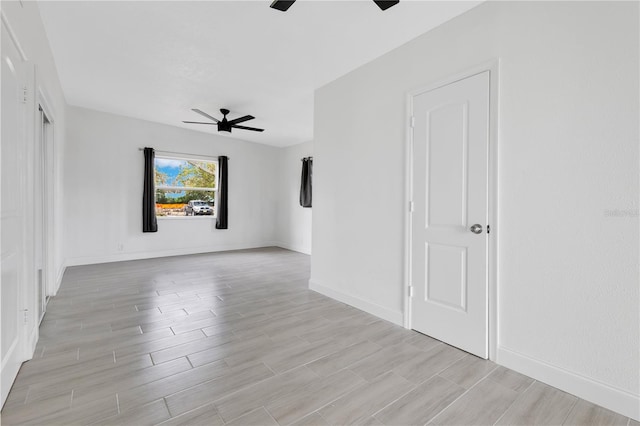 unfurnished room with ceiling fan, wood tiled floor, and baseboards