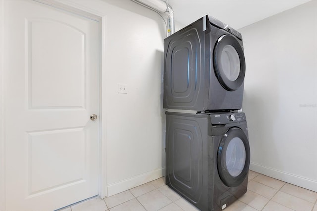 laundry area with laundry area, baseboards, stacked washing maching and dryer, and light tile patterned floors